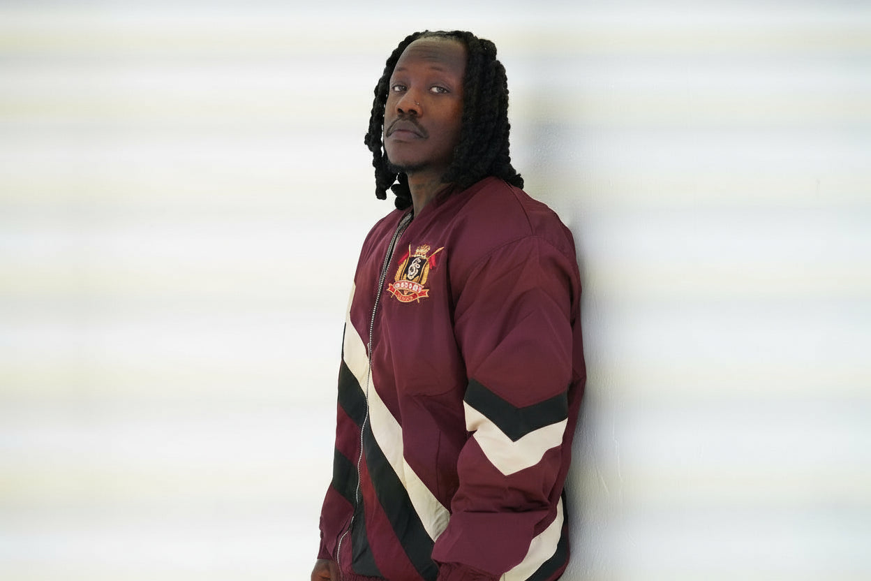 Person wearing a maroon jacket with stripes against a plain background